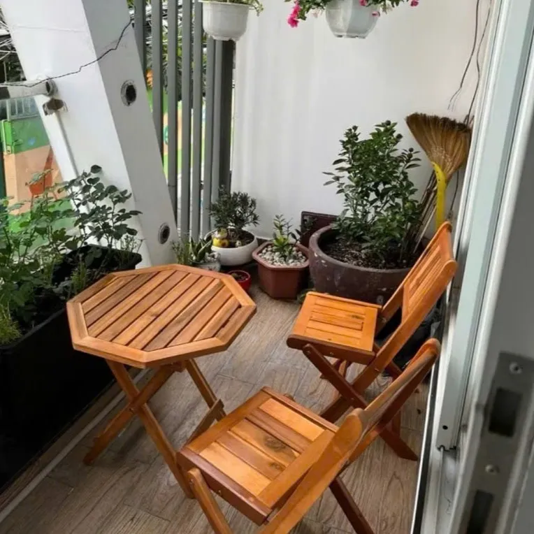 Bộ bàn ghế tiếp khách gồm bàn tròn và 4 ghế gỗ gấp gọn, thiết kế đơn giản đặt trong không gian ngoài trời, phù hợp sử dụng linh hoạt trong nhà và sân vườn